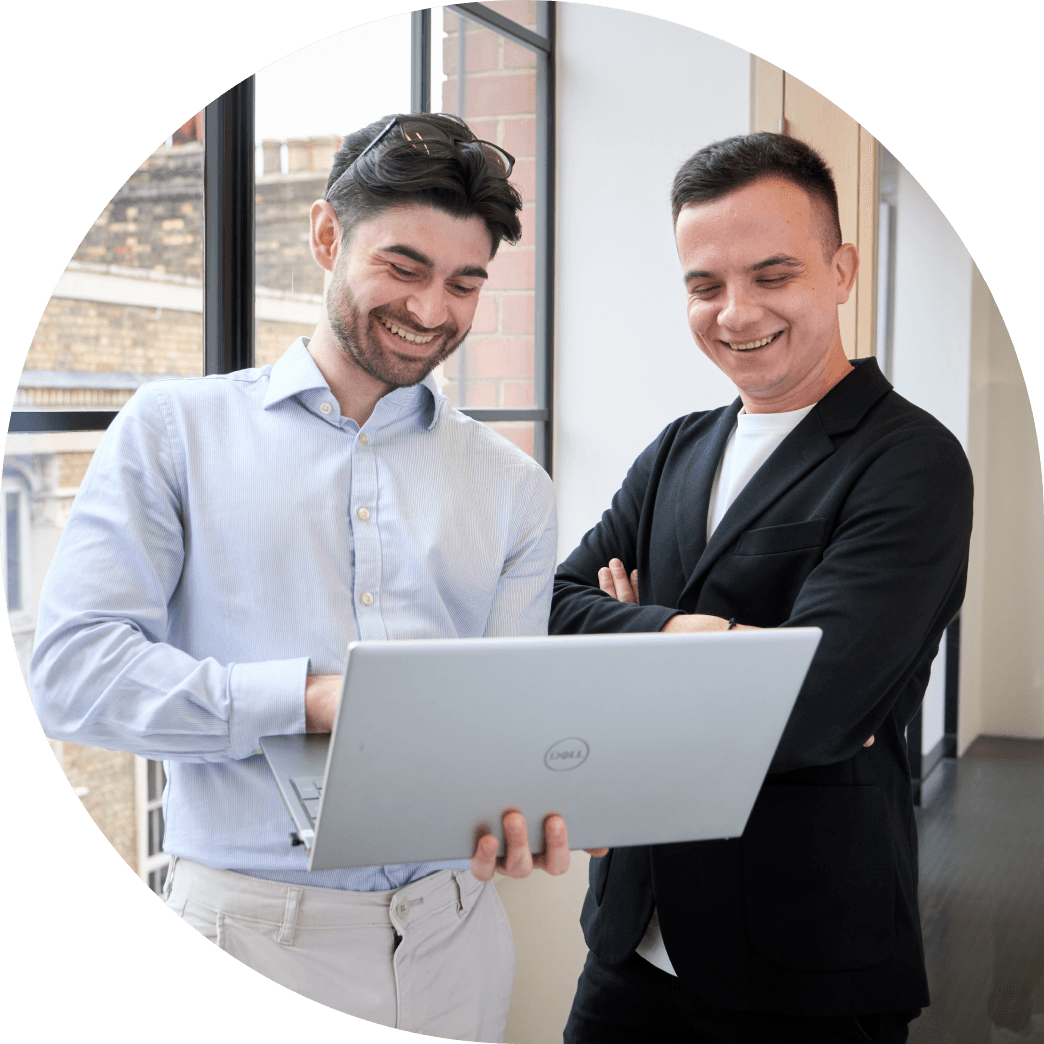 Two Fire team members smiling and looking at a laptop screen in Fire's Shoreditch office in London.