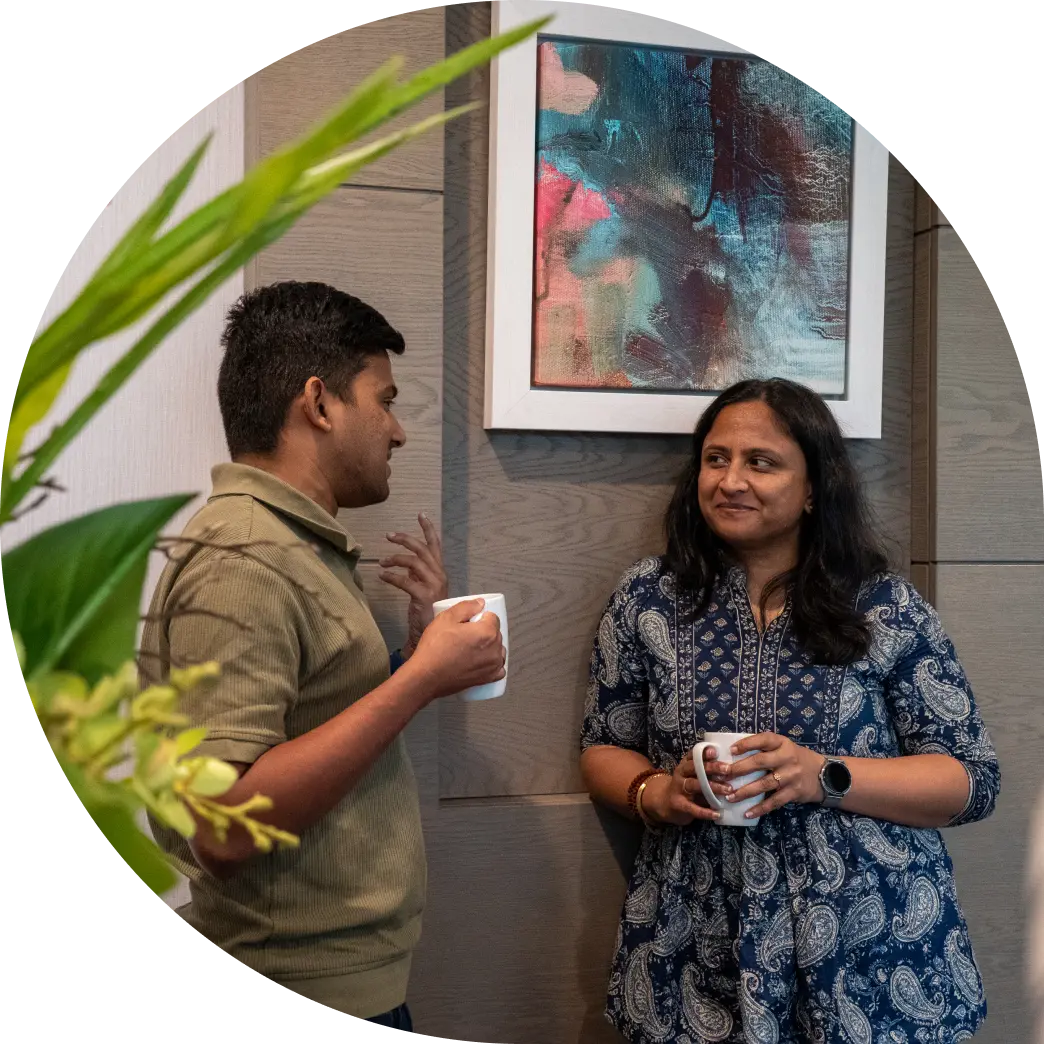 Two colleagues at Fire standing together with coffee, chatting.